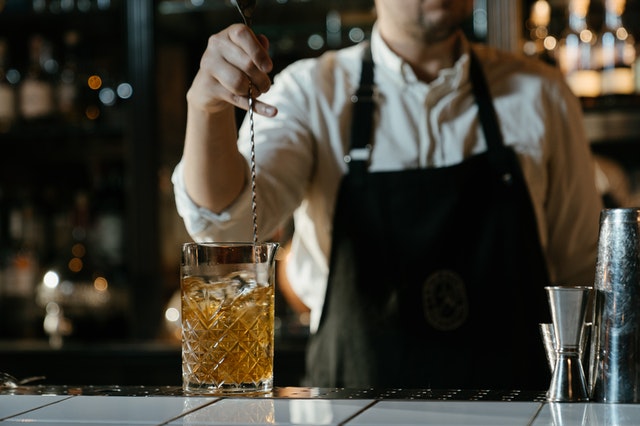 Man mixing drink with bar spoon